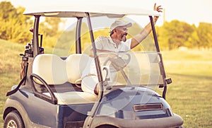 Senior man driving golf car