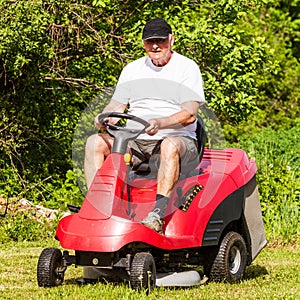 Senior man driving a red lawn mower