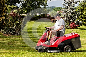 Senior man driving a red lawn mower