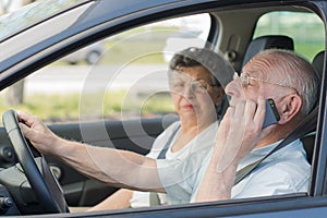 senior man driving while using phon e