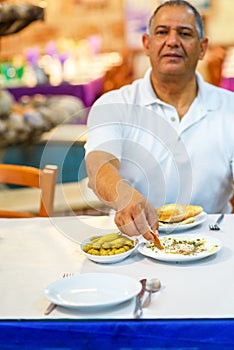 Senior man eat labneh with pita bread.