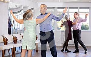 Senior man and elderly woman are dancing classic version of waltz in couple