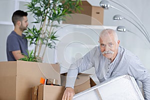 senior man in empty room with packed moving boxes