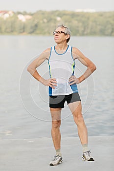 senior man is engaged in sports on the lake embankment