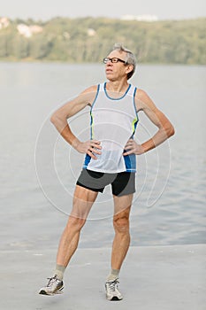 senior man is engaged in sports on the lake embankment