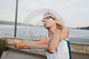 senior man is engaged in sports on the lake embankment