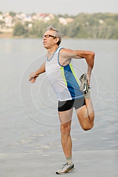 senior man is engaged in sports on the lake embankment