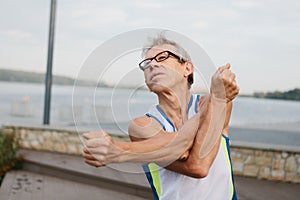 senior man is engaged in sports on the lake embankment