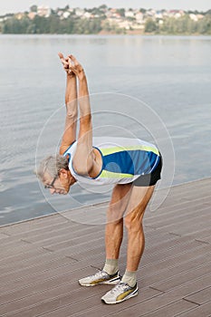 senior man is engaged in sports on the lake embankment