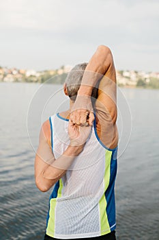 senior man is engaged in sports on the lake embankment