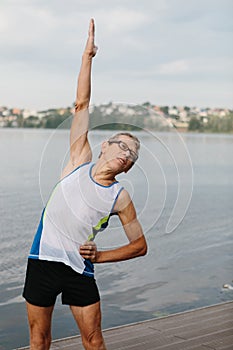 senior man is engaged in sports on the lake embankment