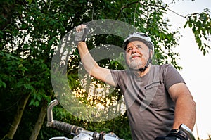 Senior man enjoying lovely bike or cycling in the forest during lovely summer sunset, healthy lifestyle concept