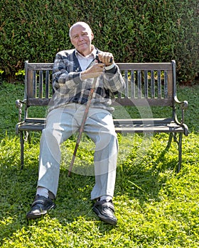 Senior man enjoys sitting on a bench in his garden