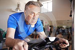 Senior Man Exercising On Cycling Machine In Gym