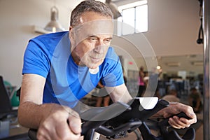 Senior Man Exercising On Cycling Machine In Gym