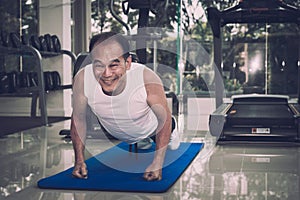 Senior man exercising by doing push ups in the fitness center,