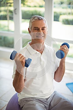 Senior man exercising with dumbells at home