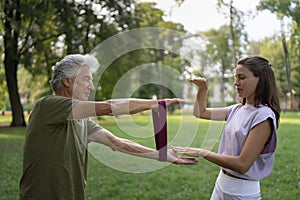 The senior man exercising in the park, using resistance band.