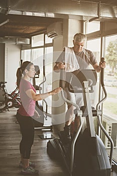 Senior man exercising on stationary bikes in fitness class.