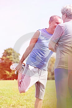 Senior man exercising while woman standing in park