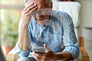 Senior man experiencing pain while using a smartphone photo