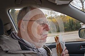 Senior man with expressive face eating fast foods