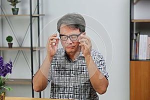 Senior man eye strain after for long stretches at computer screens