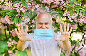 Senior man face mask. Respiratory mask. Pollen allergen. Man and flowers. Allergic reaction. Limit risk infection