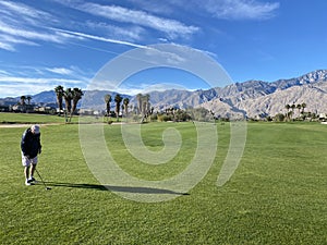 A senior man on the fairway about to hit a golf ball on a beautiful day in Palm Springs, California, USA,