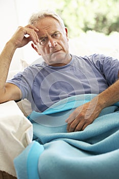 Senior Man Feeling Unwell Resting Under Blanket photo