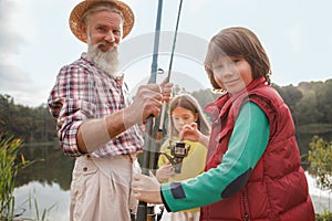 Senior man fishing on lake with his grandchildren