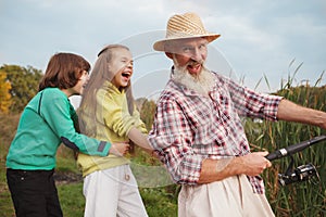 Senior man fishing on lake with his grandchildren