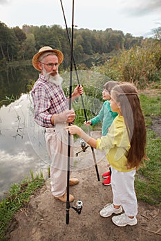 Senior man fishing on lake with his grandchildren