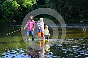 Senior man fishing with son and grandson. Grandpa and grandson are fly fishing on river. Men hobby. Summer day. Family