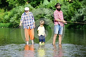 Senior man fishing with son and grandson. Summer weekend. Happy grandfather and grandson are fishing on the river.