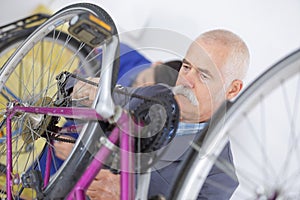 Senior man fixes granddaughters bikes brakes