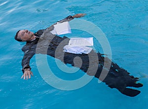 Senior man floating among papers in water