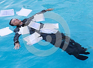 Senior man floating among papers in water