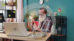 Senior man freelancer taking break from work wearing 3D glasses eating popcorn watching movie film