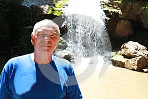 Senior man in front of waterfall Shum on rufabgo stream