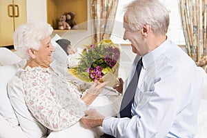 Senior Man Giving Flowers To His Wife In Hospital