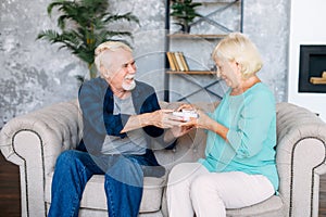 Senior man giving a gift to senior woman at home