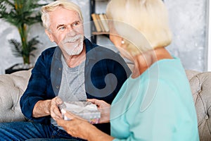 Senior man giving a gift to senior woman at home