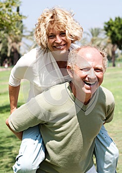 Senior man giving piggy ride to her wife