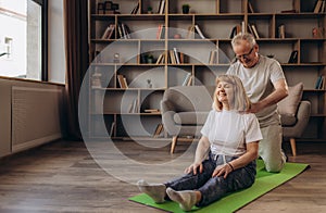 senior man giving a shoulder massage to his wife on sofa