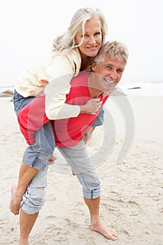 Senior Man Giving Woman Piggyback On Winter Beach