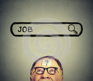 Senior man in glasses looking up searching for a job.