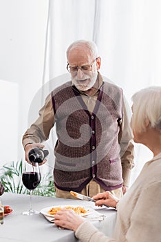 senior man in glasses pouring red