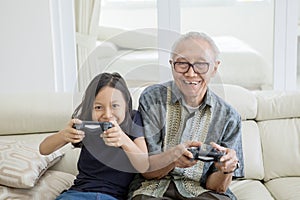 Senior man and granddaughter playing video games