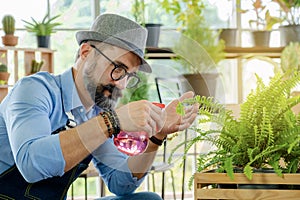 A senior man or grandfather with a mustache enjoys gardening for the tree at home after retirement